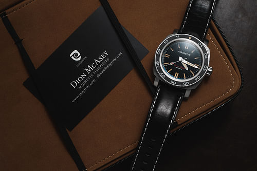 The Magrette Waterman timepiece sits next to custom UV-coated business cards